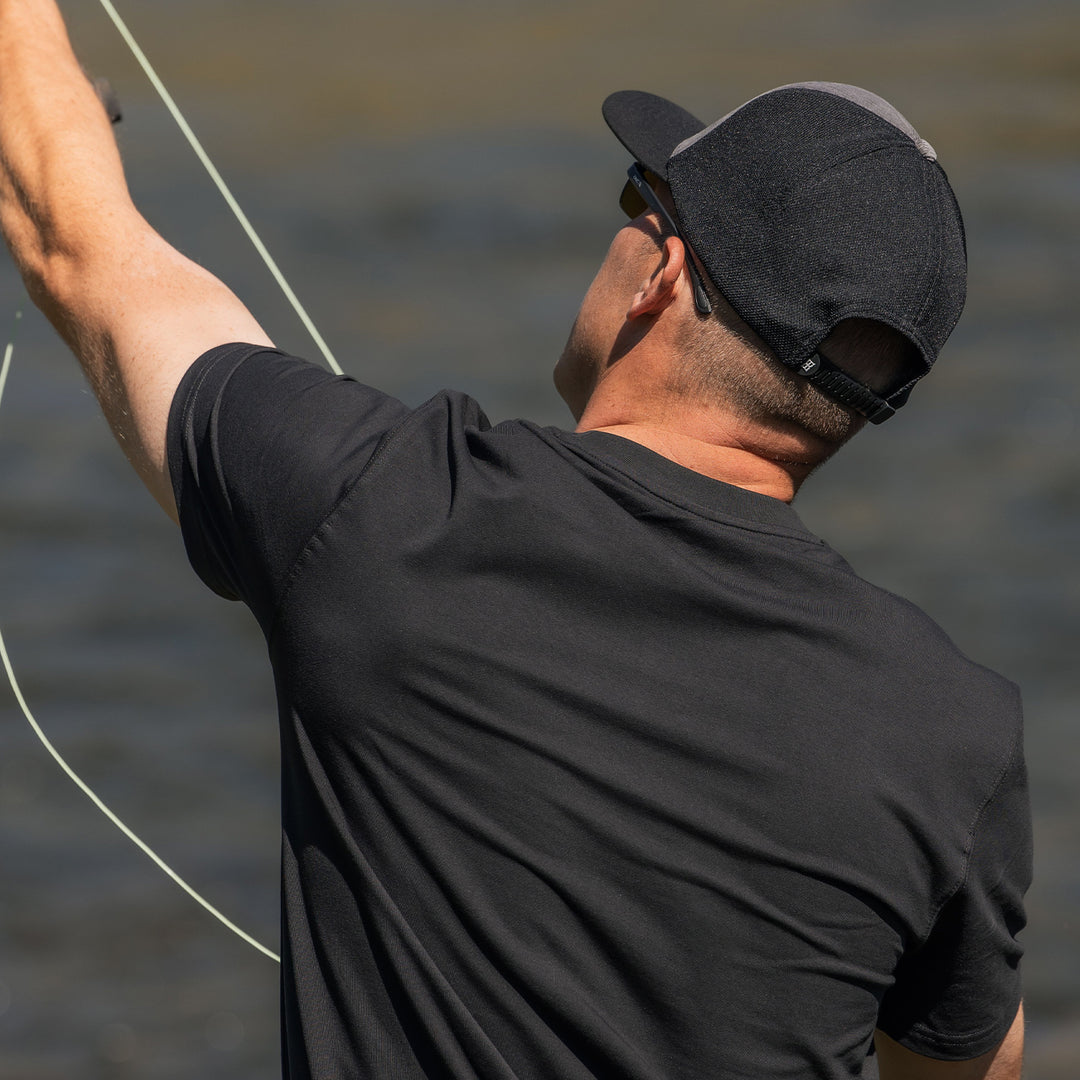 Man wearing corduroy classic cap with performance mesh back outdoors fishing at the lake #color_dark-gray