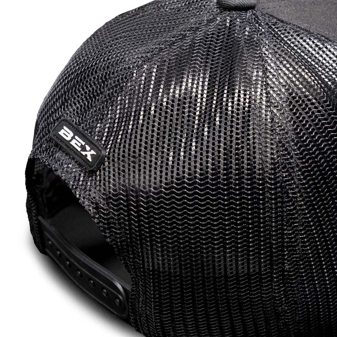 Close-up view of the Steel Black cap’s mesh back, featuring a small silicone BEX patch above the snapback closure #color_black